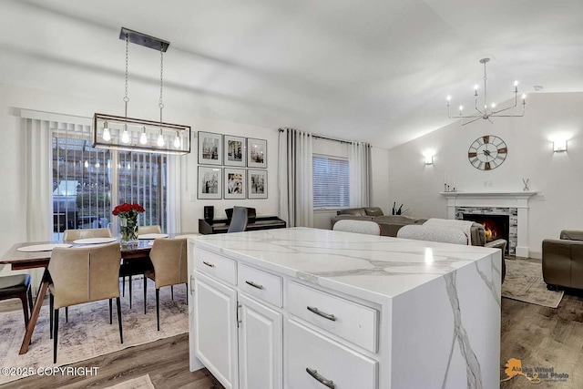 kitchen with white cabinetry, dark hardwood / wood-style floors, decorative light fixtures, a fireplace, and a kitchen island