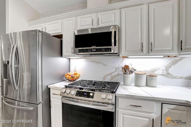 kitchen with light stone counters, white cabinets, stainless steel appliances, and tasteful backsplash