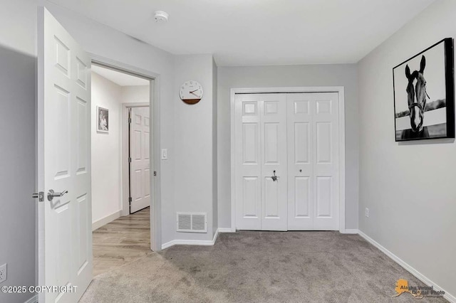 unfurnished bedroom with light carpet and a closet