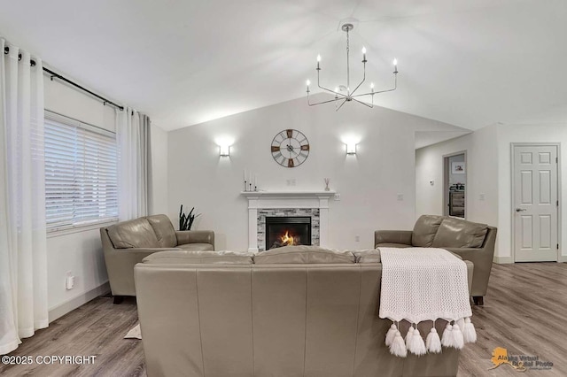 living room featuring a fireplace, an inviting chandelier, lofted ceiling, and light wood-type flooring