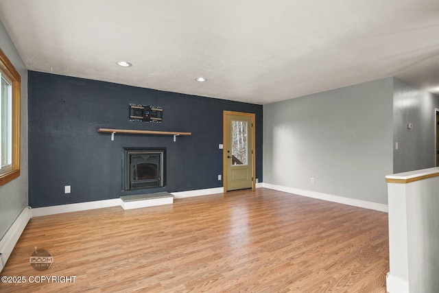 unfurnished living room featuring baseboard heating and light hardwood / wood-style flooring