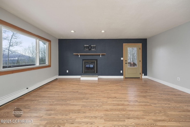 unfurnished living room featuring a baseboard heating unit and light hardwood / wood-style flooring