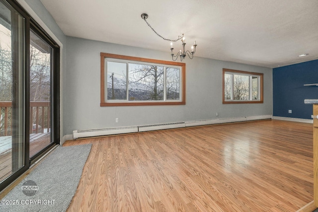 spare room with a baseboard heating unit, an inviting chandelier, and wood-type flooring