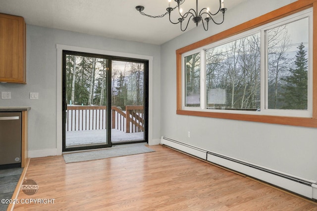 interior space featuring light wood-type flooring, a baseboard heating unit, and a notable chandelier