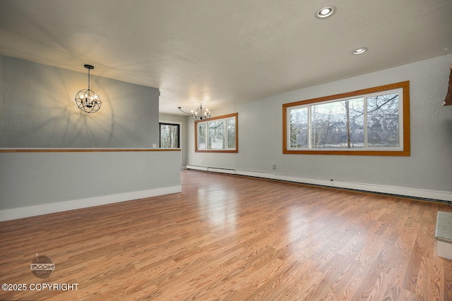 unfurnished room featuring a baseboard heating unit, light hardwood / wood-style floors, and a notable chandelier