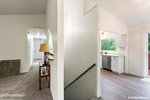 corridor featuring lofted ceiling, light carpet, and sink