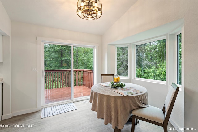 dining area with vaulted ceiling, light hardwood / wood-style flooring, and an inviting chandelier