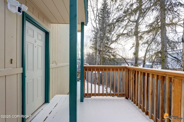 snow covered property entrance with a wooden deck