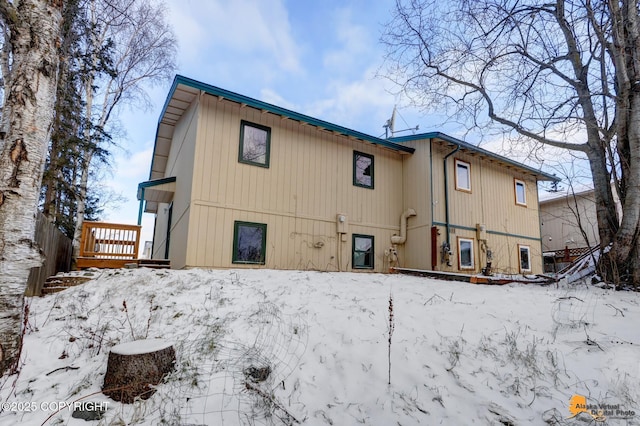 snow covered back of property with a wooden deck