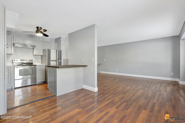 kitchen with appliances with stainless steel finishes, dark wood-type flooring, ceiling fan, and kitchen peninsula