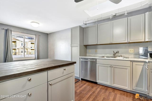 kitchen with dark wood-type flooring, sink, butcher block countertops, stainless steel dishwasher, and ceiling fan