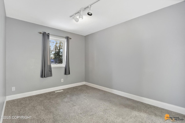 unfurnished room featuring track lighting and carpet flooring