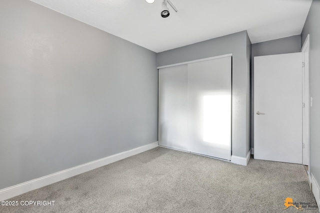 unfurnished bedroom with light colored carpet and a closet