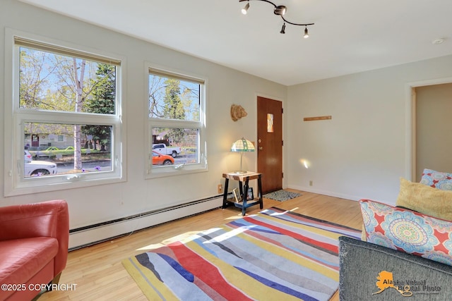 bedroom with baseboard heating, multiple windows, and wood finished floors