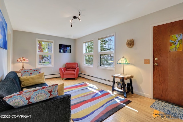 living area featuring a baseboard radiator, light wood-style flooring, track lighting, and baseboards