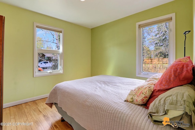 bedroom featuring multiple windows, wood-type flooring, and baseboards