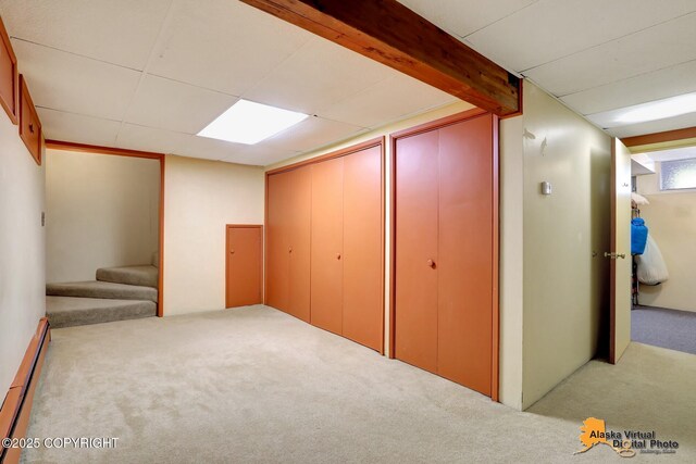 basement featuring carpet floors, a baseboard radiator, and stairway