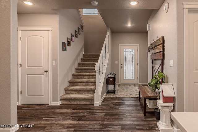 foyer entrance with dark hardwood / wood-style floors and a textured ceiling