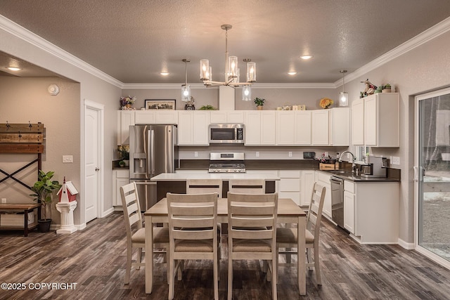 kitchen featuring ornamental molding, appliances with stainless steel finishes, sink, and hanging light fixtures