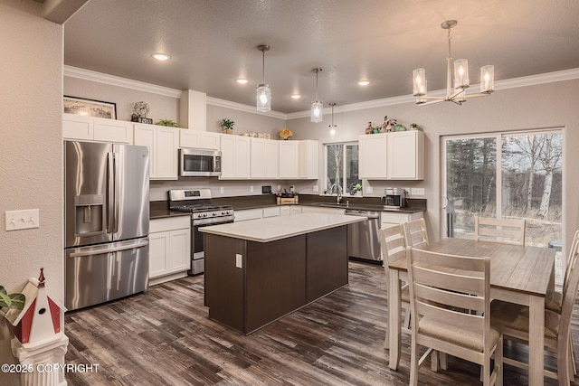 kitchen featuring sink, dark wood-type flooring, appliances with stainless steel finishes, a kitchen island, and decorative light fixtures