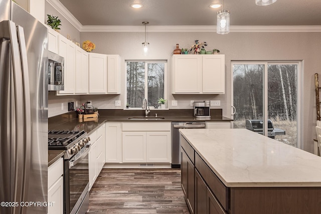 kitchen with white cabinetry, appliances with stainless steel finishes, sink, and decorative light fixtures