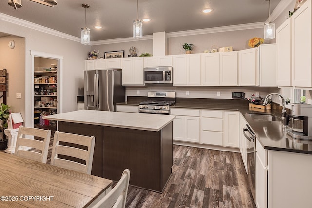 kitchen with stainless steel appliances, a kitchen island, hanging light fixtures, and sink