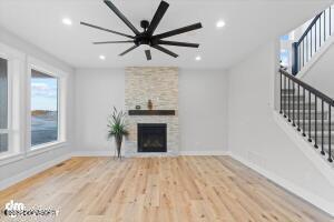 unfurnished living room with light hardwood / wood-style floors, ceiling fan, and a stone fireplace