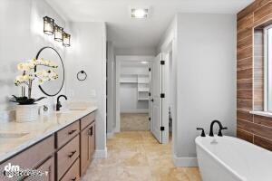 bathroom featuring double vanity, a freestanding tub, a spacious closet, and a sink