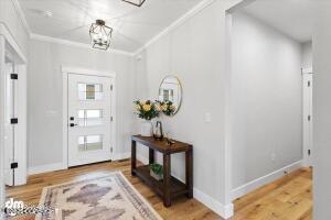 foyer entrance featuring ornamental molding, light hardwood / wood-style flooring, and an inviting chandelier