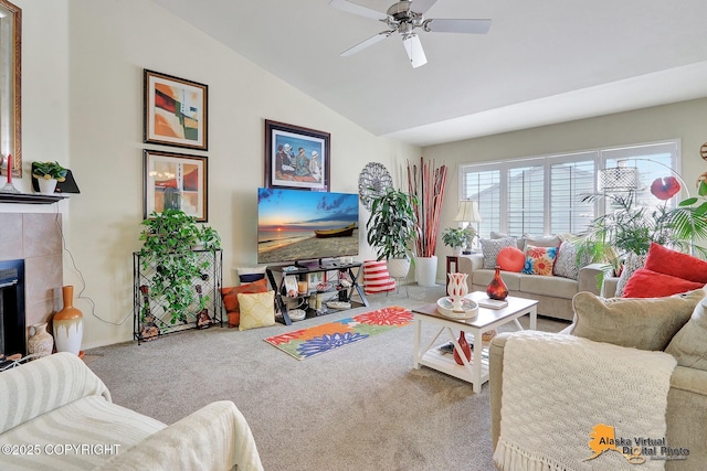 carpeted living area featuring ceiling fan, a tile fireplace, and vaulted ceiling