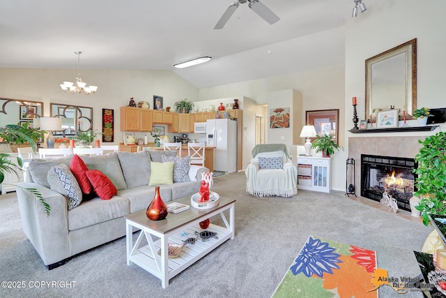 living room featuring lofted ceiling, light carpet, a tiled fireplace, and ceiling fan with notable chandelier