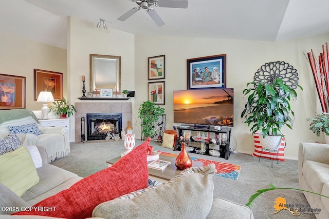 living room with a tile fireplace, a ceiling fan, carpet, and vaulted ceiling