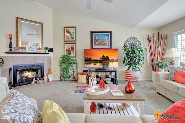 carpeted living area with a tiled fireplace, baseboards, lofted ceiling, and a ceiling fan