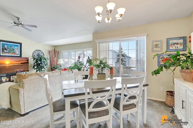 dining room featuring ceiling fan with notable chandelier, vaulted ceiling, light colored carpet, and baseboards