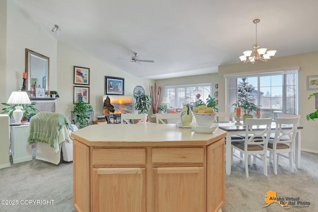 kitchen with light colored carpet, light countertops, lofted ceiling, ceiling fan with notable chandelier, and hanging light fixtures