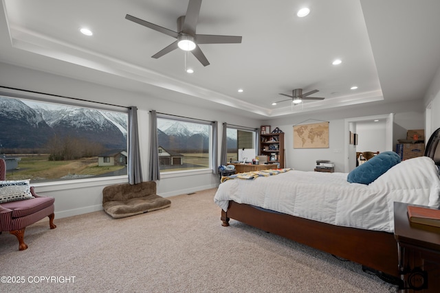 carpeted bedroom with a raised ceiling and ceiling fan