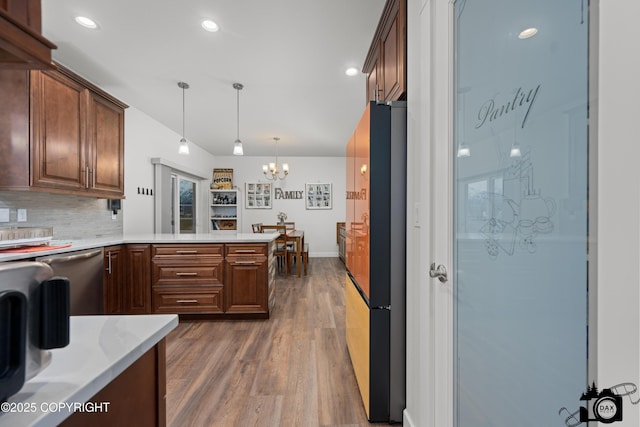 kitchen with dark wood-type flooring, refrigerator, hanging light fixtures, dishwasher, and decorative backsplash