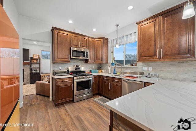 kitchen featuring pendant lighting, sink, stainless steel appliances, and hardwood / wood-style floors