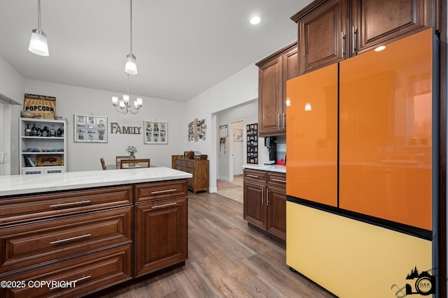 kitchen with refrigerator, a chandelier, dark hardwood / wood-style floors, pendant lighting, and light stone countertops