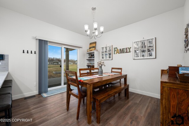 dining space featuring dark wood-type flooring and an inviting chandelier