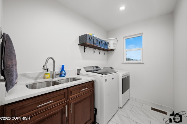 laundry room featuring separate washer and dryer, sink, and cabinets