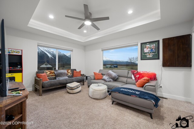 living room featuring ceiling fan, a healthy amount of sunlight, a tray ceiling, and carpet floors