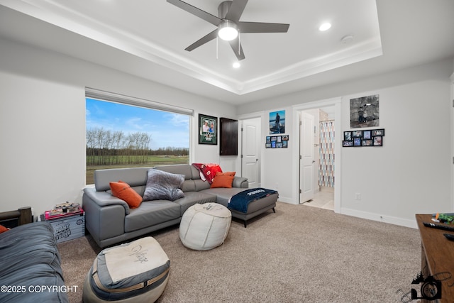 living room featuring a raised ceiling, light colored carpet, and ceiling fan