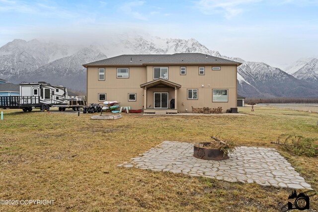 back of house with a mountain view, a yard, a patio area, and an outdoor fire pit