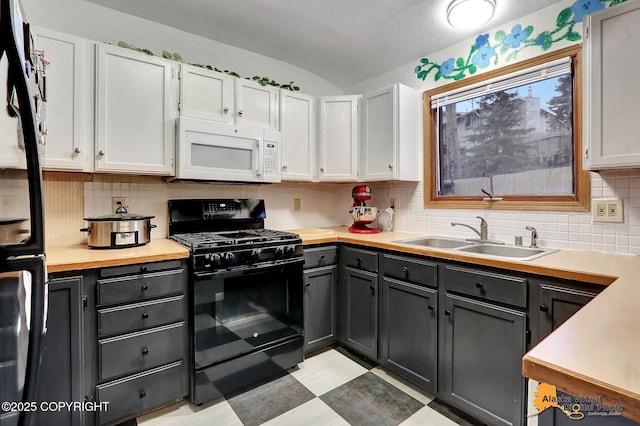 kitchen with black range with gas cooktop, sink, and white cabinets