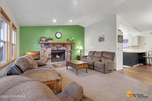 living room featuring lofted ceiling, a stone fireplace, and light hardwood / wood-style floors