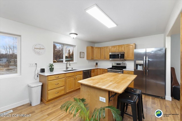 kitchen featuring sink, a breakfast bar area, a center island, light hardwood / wood-style flooring, and stainless steel appliances