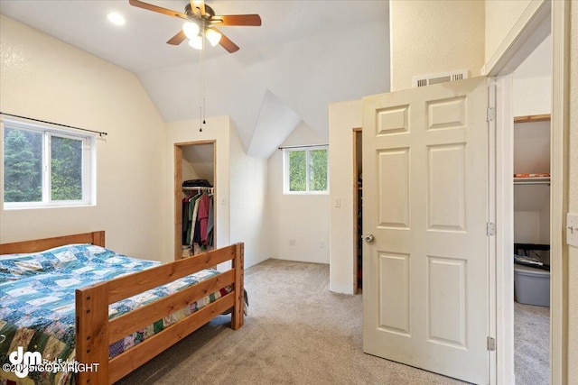 bedroom featuring a spacious closet, light carpet, a closet, vaulted ceiling, and ceiling fan