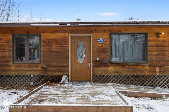 snow covered property entrance with a deck