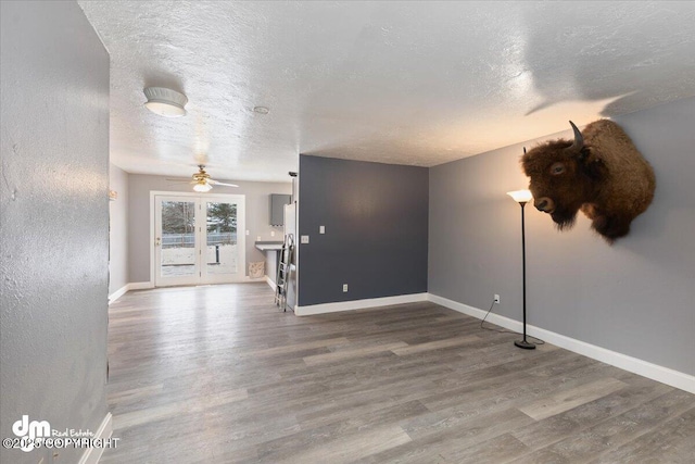 unfurnished living room featuring ceiling fan, hardwood / wood-style floors, and a textured ceiling